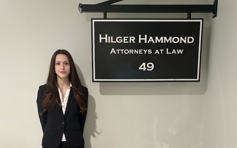 Hilger Hammond 2026 Legal intern Anna Skidmore standing in front of the firm's sign.